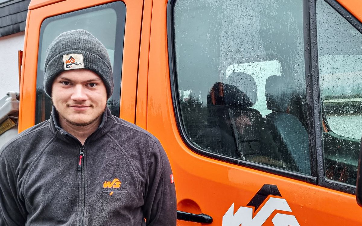 Junger Mitarbeiter von Schmittnägel Bau am gebrandeten Firmenbus in Wallenfels